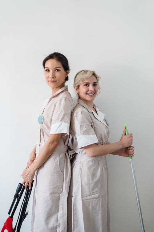 Two professional Spotless cleaning team members standing back to back, ready to clean homes in Paphos