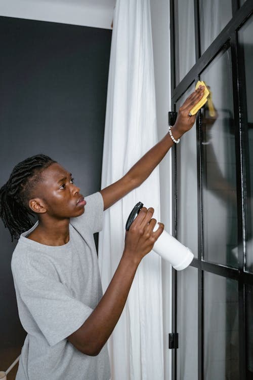 Professional cleaner using spray bottle to clean glass panels in a commercial office in Paphos
